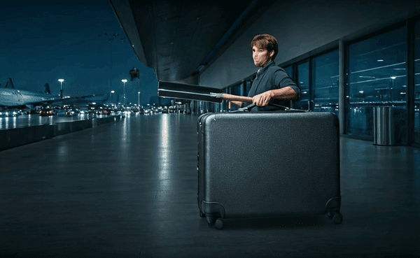 alt_text: Osoba pakująca elektronikę do walizki na lotnisku, skupiona i dbająca o bezpieczeństwo sprzętu.