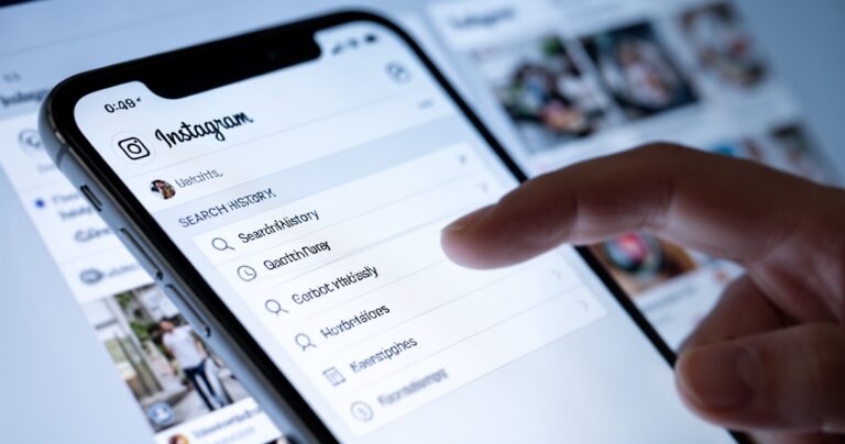 Smartfon z otwartą aplikacją Instagram, palec wskazujący na ustawienia historii wyszukiwania